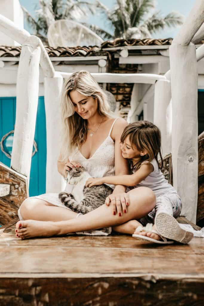 woman and child sitting and petting a cat