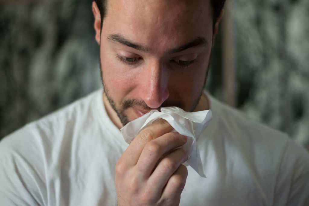 man wiping nose with tissue paper