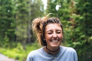 woman smiling outdoor next to trees during daytime