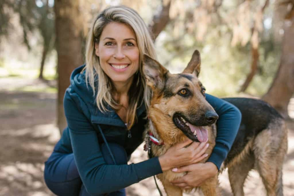 A woman in blue jacket hugging her dog