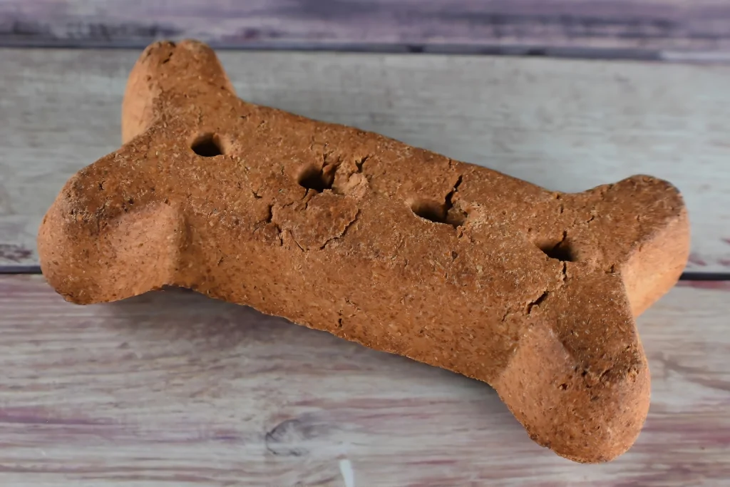 a single piece of a dog treat cookie on wooden surface