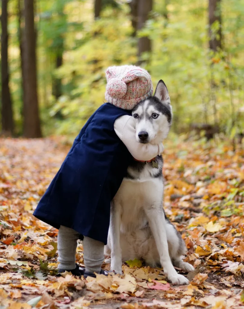 little girl hugging a dog in the forest