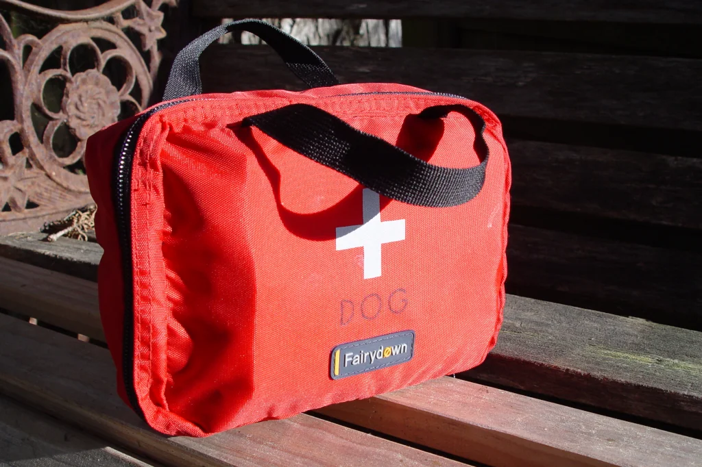 red first aid kit for dog on a wooden bench